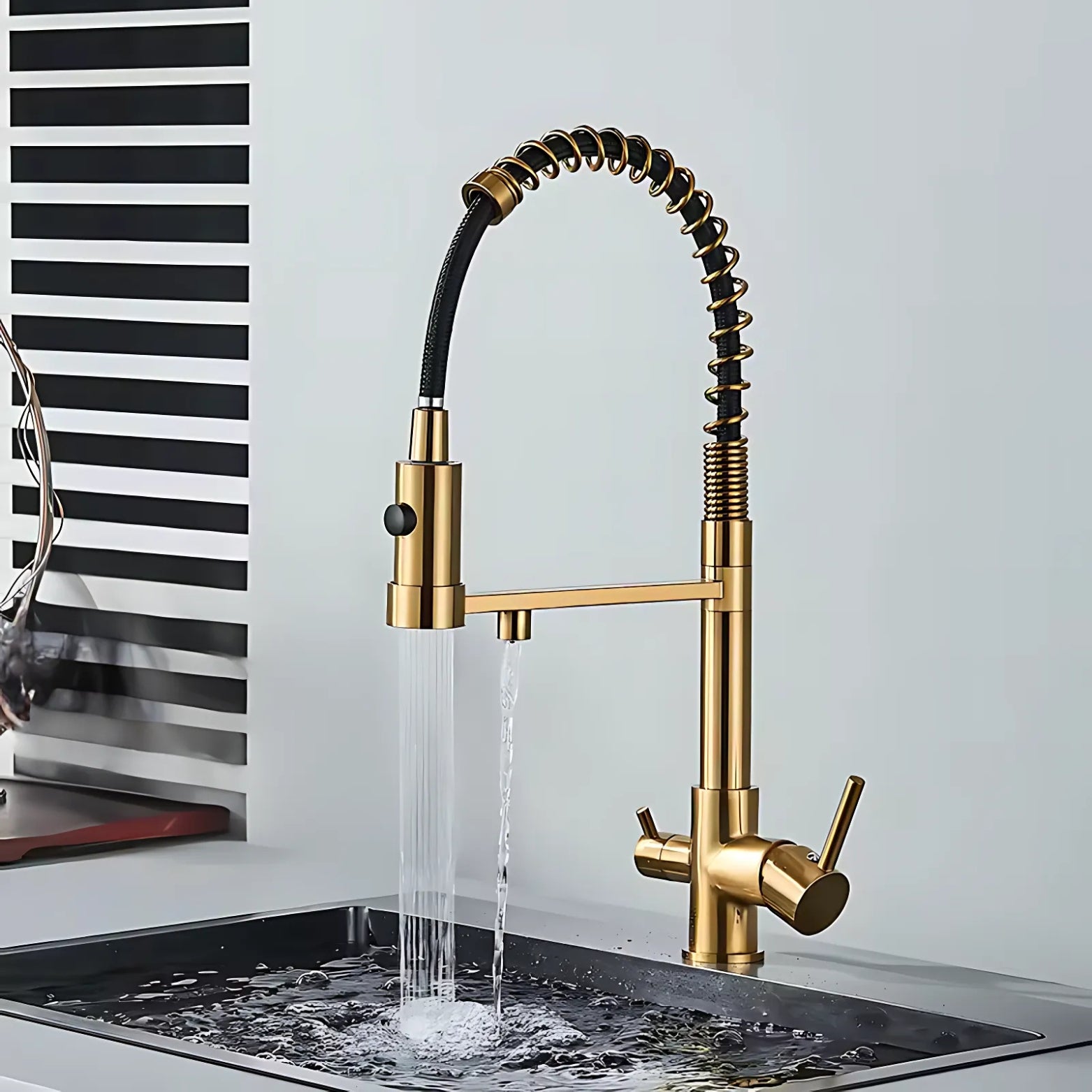 Gold kitchen faucet with water flowing into a sink against a light gray background.