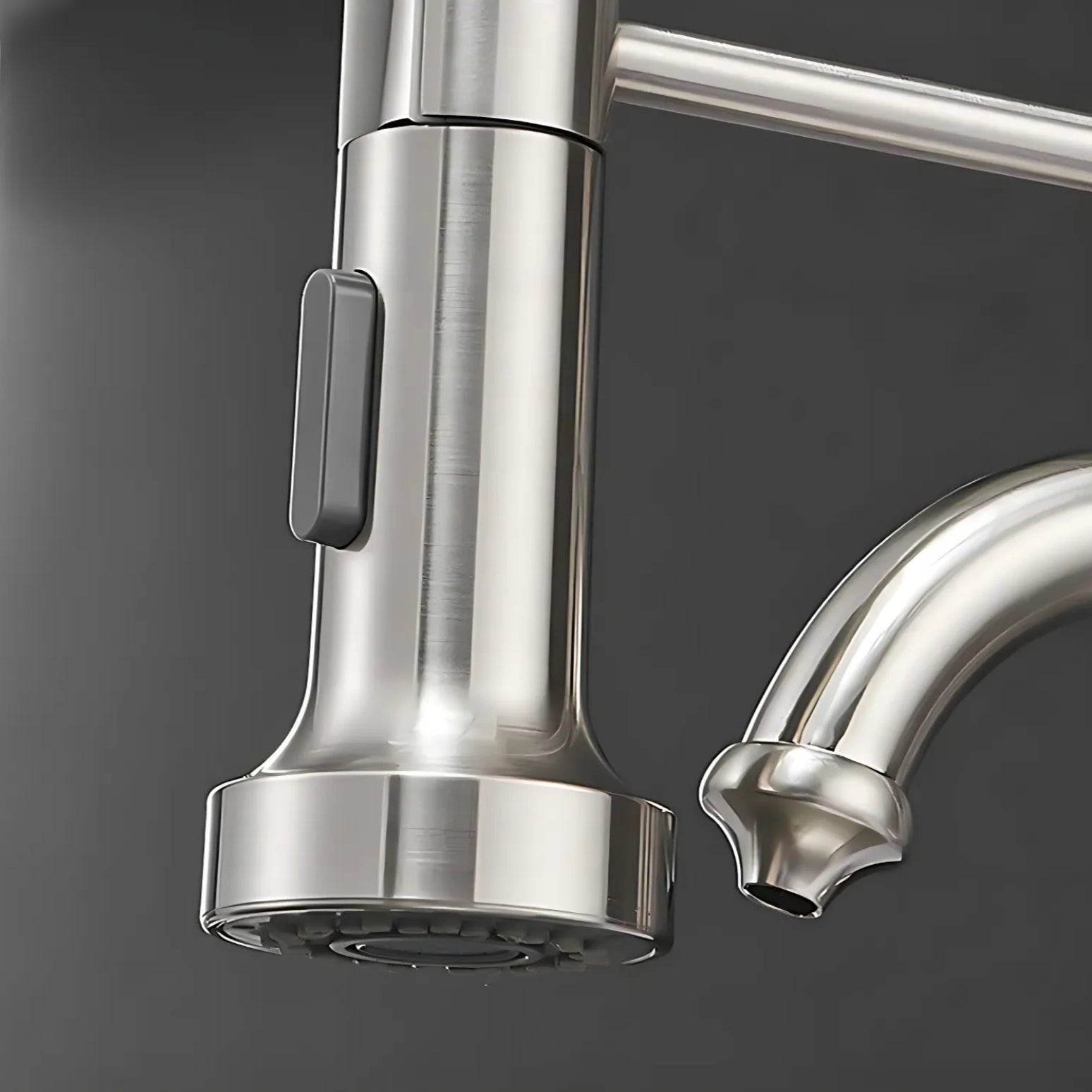 Stainless steel kitchen faucet with spray head on a dark background
