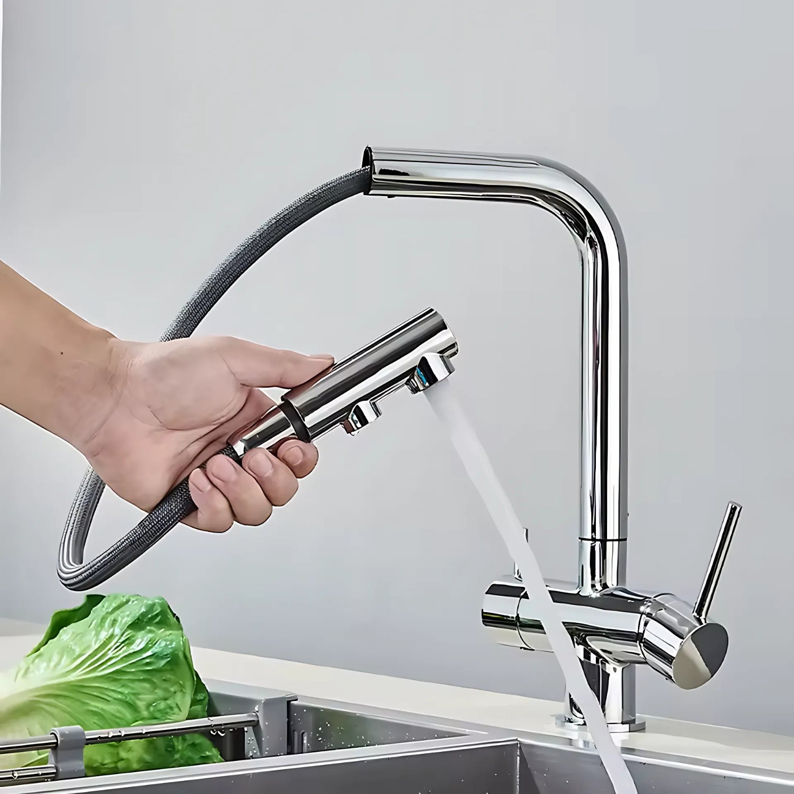 3-Way Pull-Out Person using a kitchen faucet with a handheld sprayer to wash vegetables in a sink.