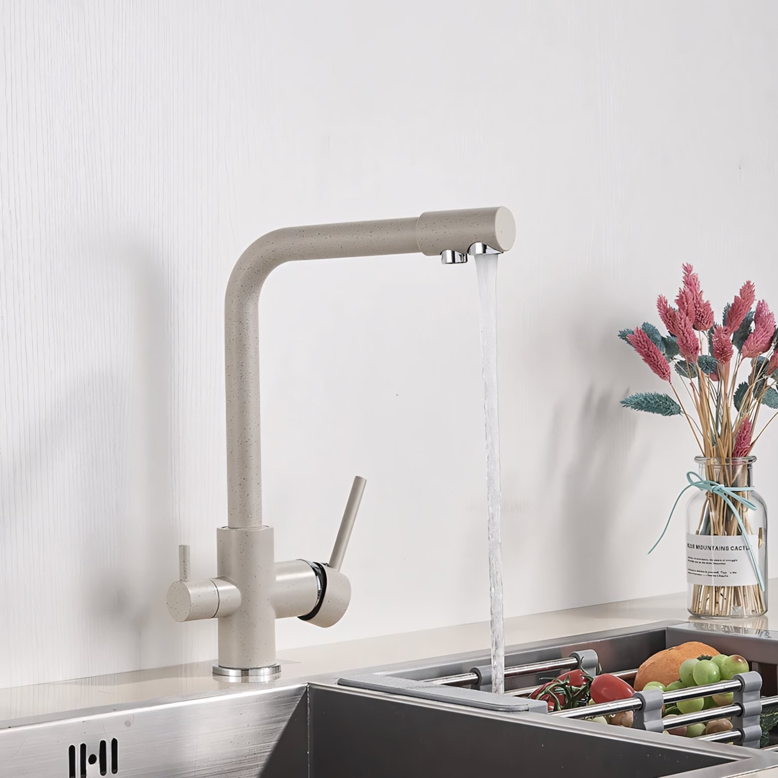 Modern kitchen faucet with running water, sink, and fruits on a light background