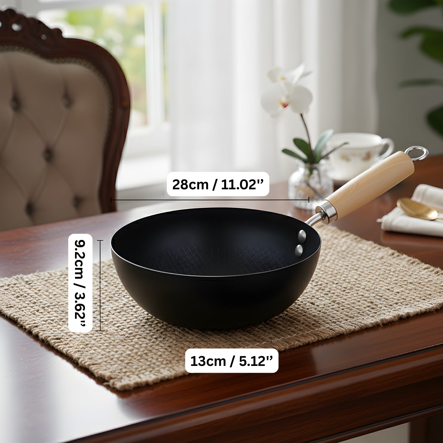 Black wok with wooden handle on a table, measurements displayed