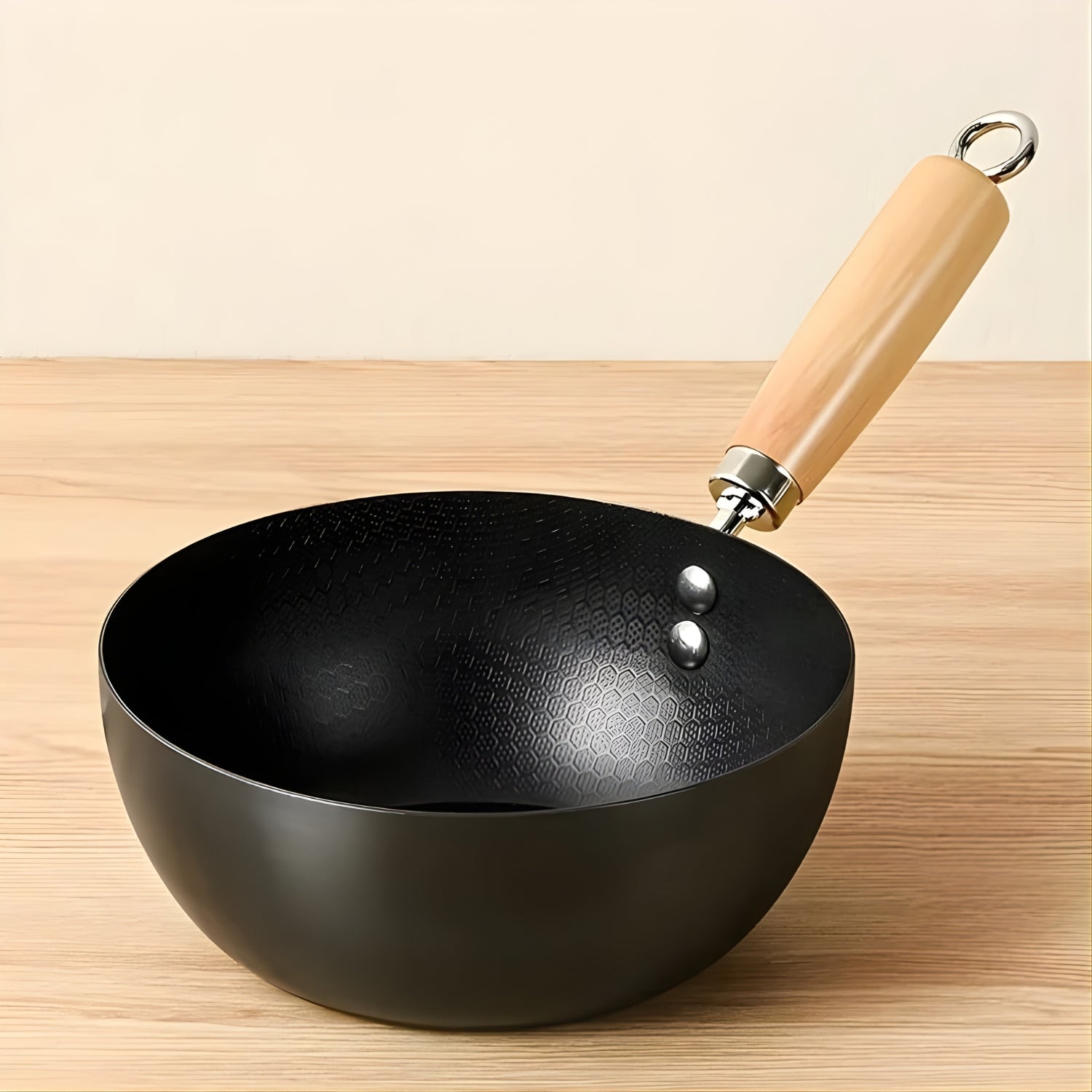 Black wok with a wooden handle on a wooden surface