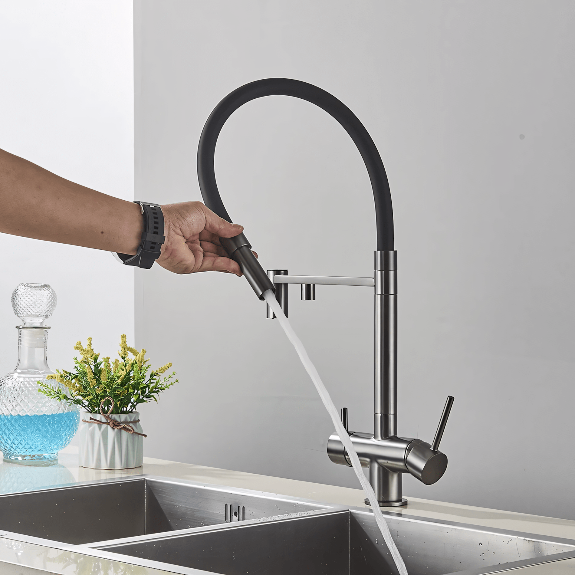 Person adjusting a modern kitchen faucet over a sink with a blurred background