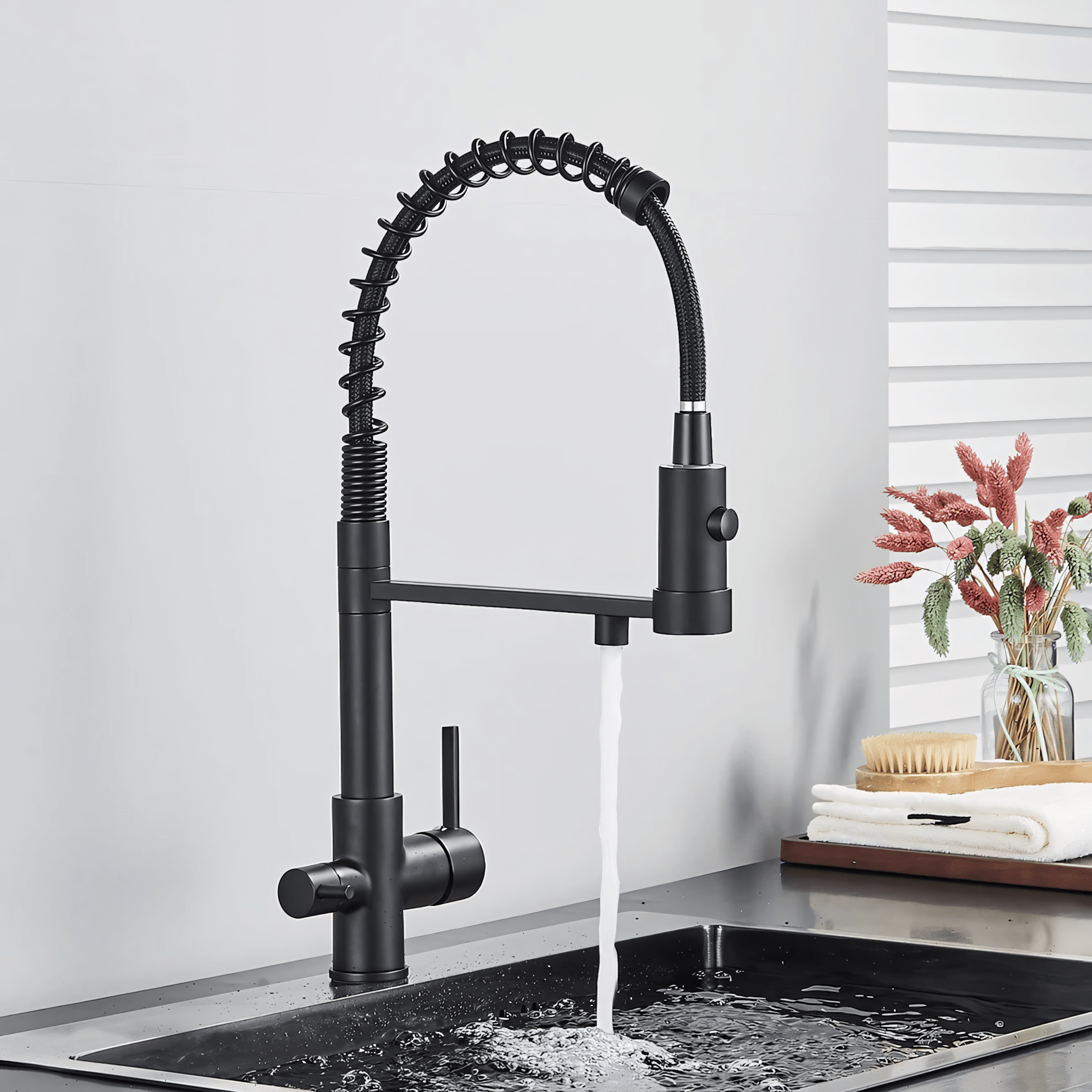 Black kitchen faucet with water flowing into a sink in a modern kitchen setting.