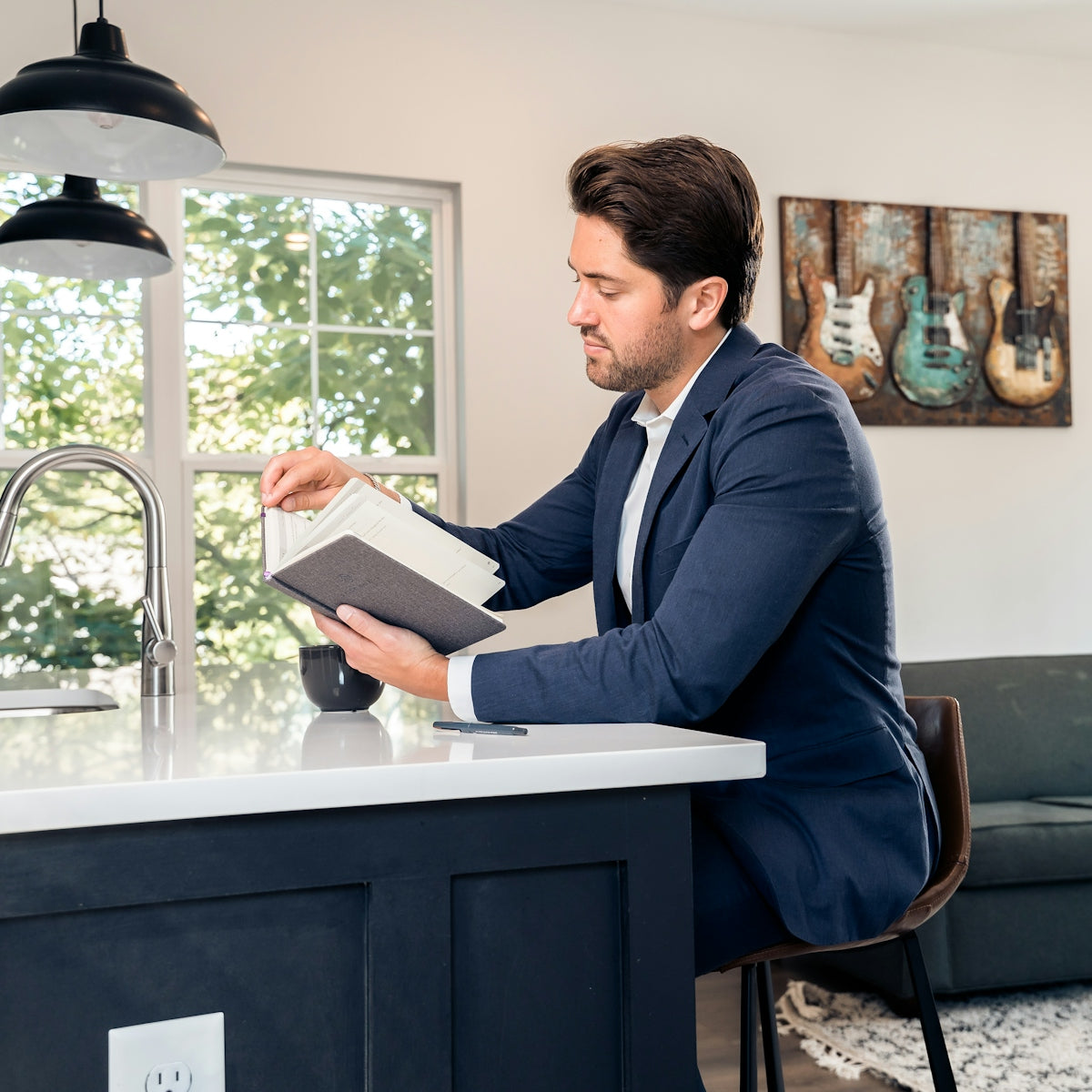 man in blue suit jacket reading book