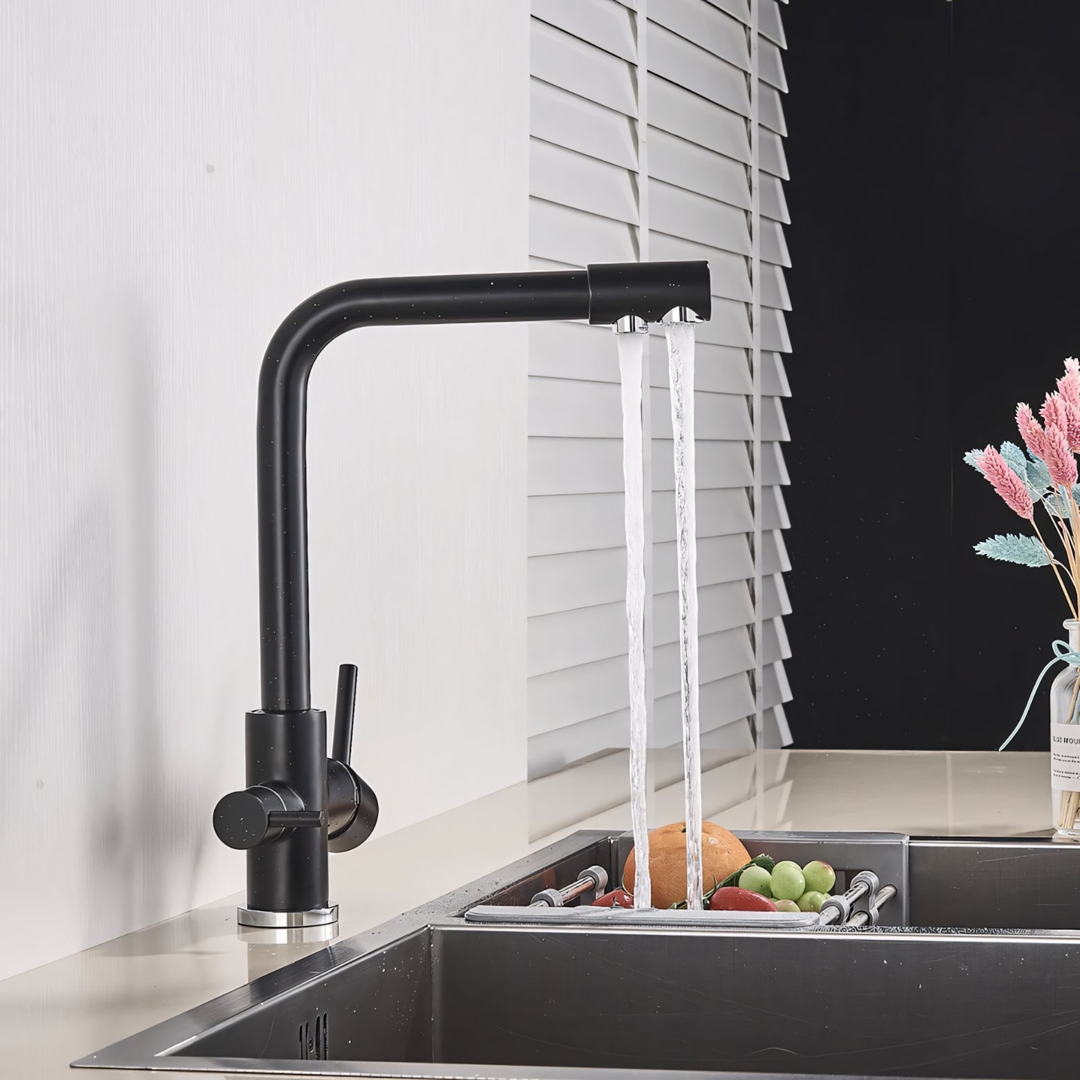 Black kitchen faucet with running water over a sink containing fruits and vegetables.